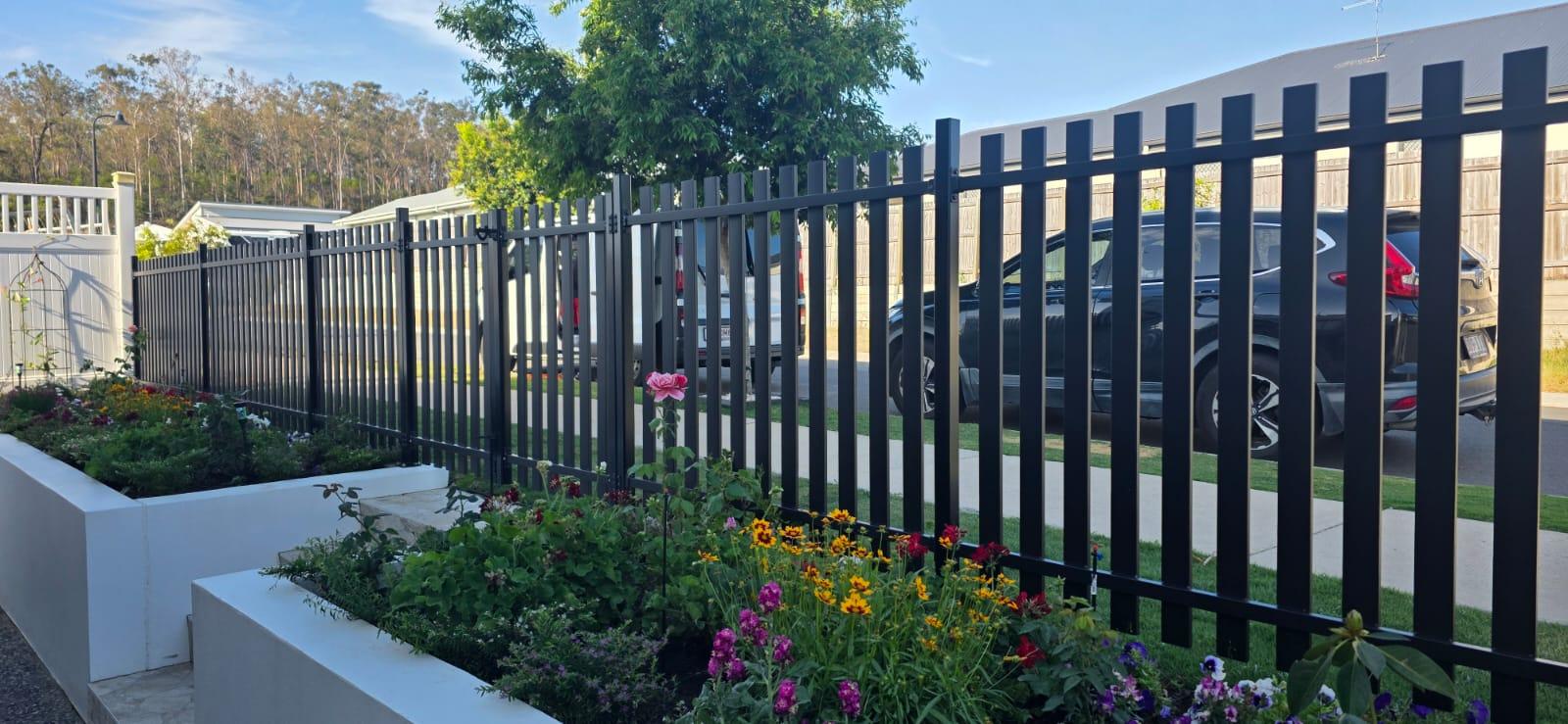 Crew installing new fencing beside a landscaped driveway
